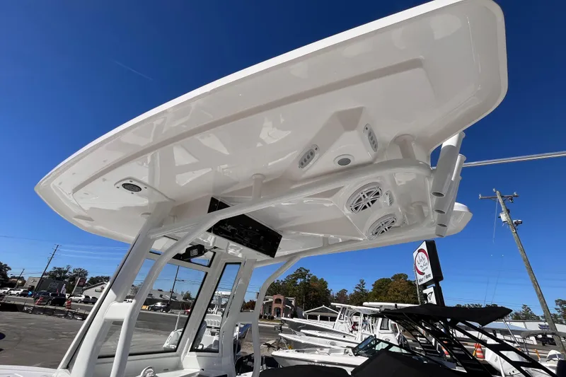 Slide: The Image of 2026 Tidewater 2410 Bay Max boat with T-top and speakers, under clear blue sky. - 13