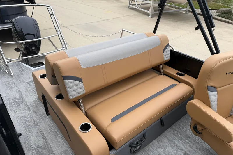Slide: The Image of 2025 Crest Classic 220 boat interior with tan and gray seating, cup holders, and motor. - 11