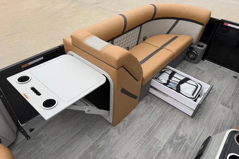 Slide: The Image of 2025 Crest Classic 220 boat interior with tan seating, fold-out table, and storage drawer. - 8