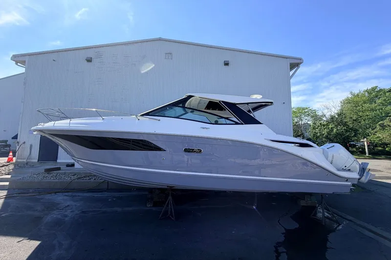 Slide: The Image of Sea Ray Sundancer 320 Outboard 2026 on a trailer in front of a building. - 9