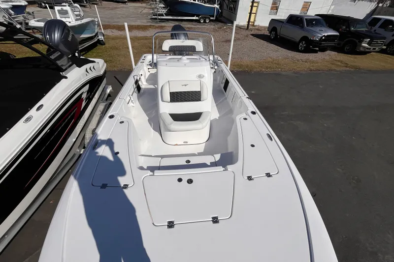 Slide: The Image of 2026 Tidewater 2110 Bay Max boat, white deck, parked outdoors, surrounded by other boats and vehicles. - 8