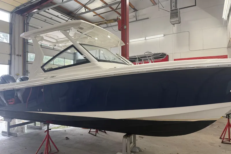 The Image of 2020 Edgewater 262CX Crossover boat in a garage, blue and white exterior. - 1