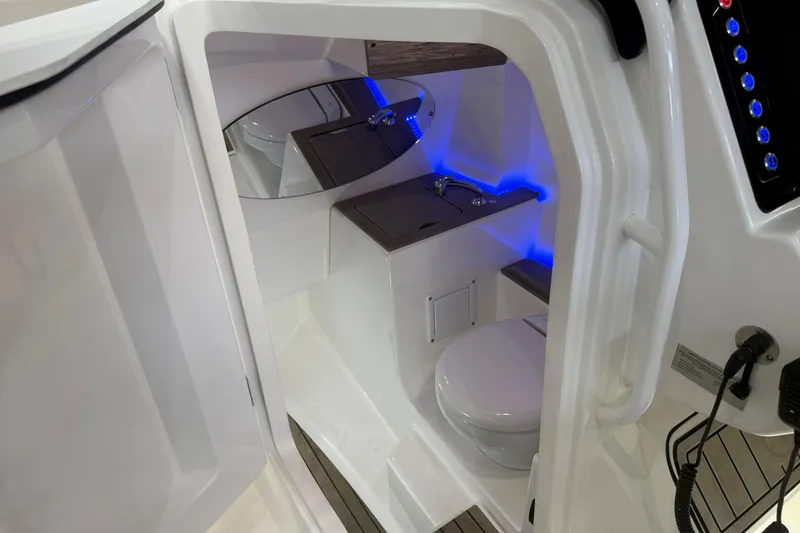 Slide: The Image of 2020 Edgewater 262CX Crossover boat interior with modern bathroom and blue LED lighting. - 13