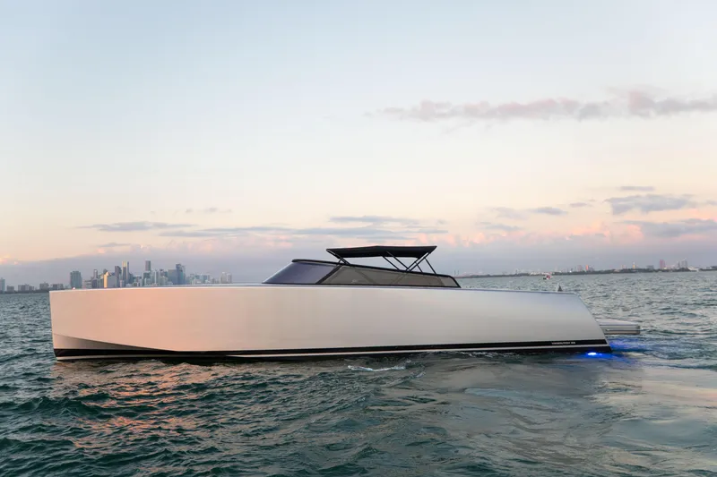 Slide: The Image of VanDutch 55 yacht cruising on water at sunset, city skyline in background, 2017 model. - 10