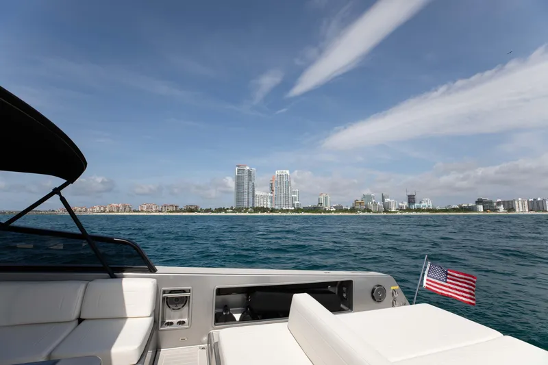 Slide: The Image of VanDutch 55 yacht cruising near a city skyline, American flag visible, 2017 model. - 12
