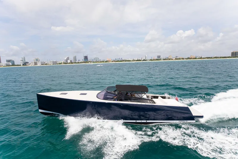 Slide: The Image of VanDutch 55 yacht cruising on open water, city skyline in background, 2017 model. - 28