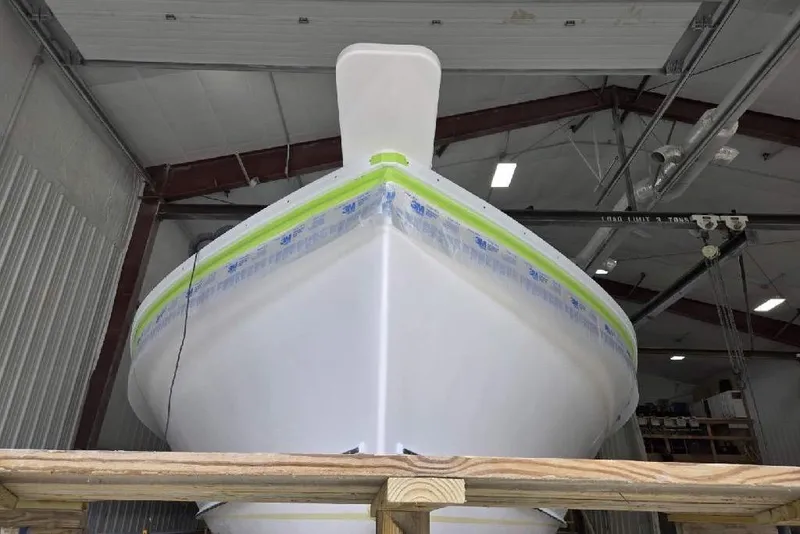Slide: The Image of Front view of a 2025 Calvin Beal Sedan boat in a workshop. - 2