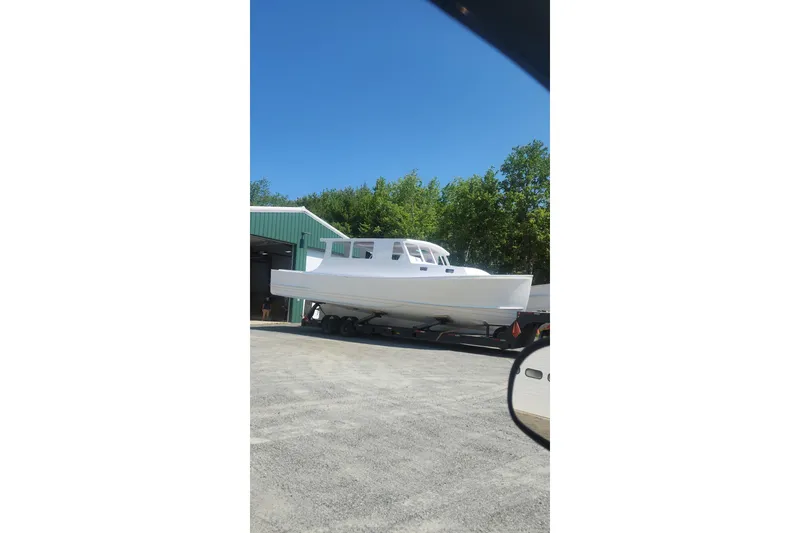 Slide: The Image of A white boat on a trailer outside a green building under a clear blue sky. - 25