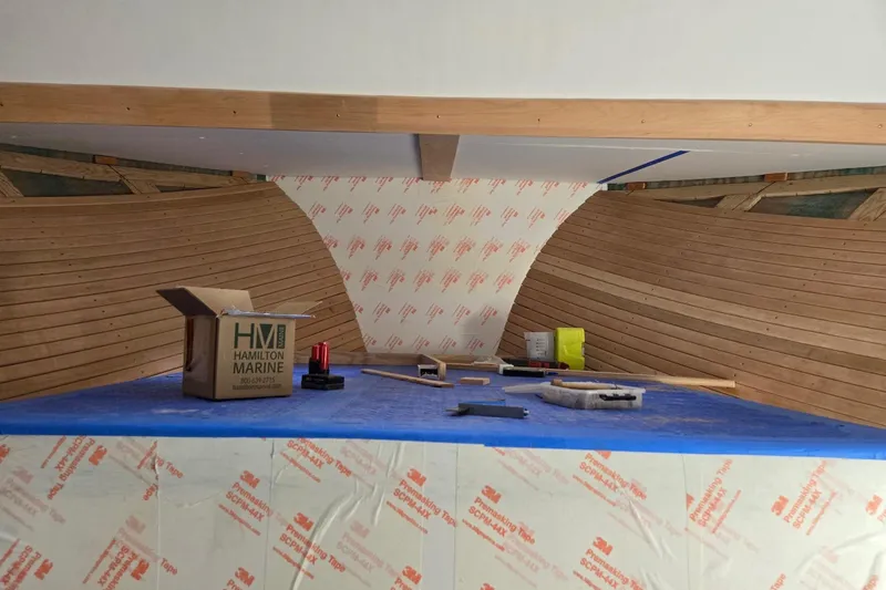 Slide: The Image of Interior construction of a 2025 Calvin Beal Sedan boat with wooden paneling and tools. - 85