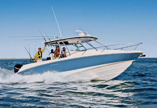 The Image of 2009 Boston Whaler 320 Outrage Cuddy Cabin boat docked near waterfront home. - 0