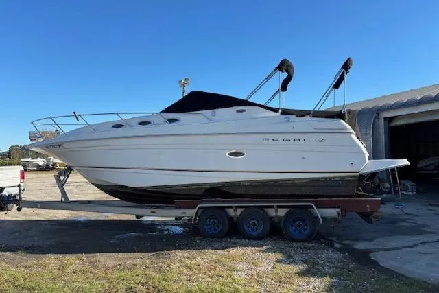 Slide: The Image of 2002 Regal Commodore 2765 boat on trailer, parked outdoors under clear blue sky. - 10