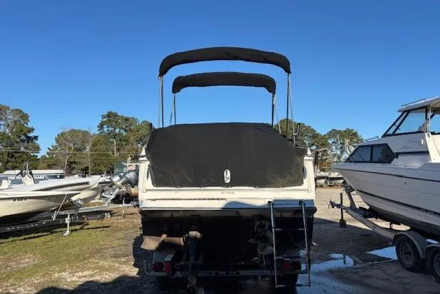 Slide: The Image of 2002 Regal Commodore 2765 boat with black canopy, parked on a trailer in a marina. - 11