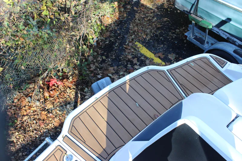 Slide: The Image of 2017 Chaparral 21 H2O Ski & Fish boat with wooden deck, surrounded by autumn leaves. - 21