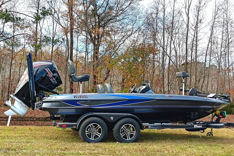 The Image of 2026 Triton 18 TrX boat on trailer, parked on grass with autumn trees in background. - 0