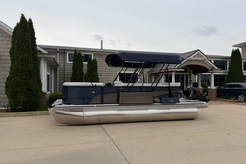 The Image of 2026 Crest Conquest 210 L pontoon boat parked outside a building with trees. - 0