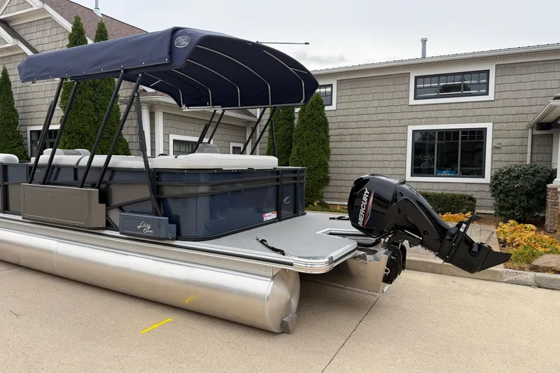Slide: The Image of 2026 Crest Conquest 210 L pontoon boat with Mercury outboard motor, parked near a house. - 4