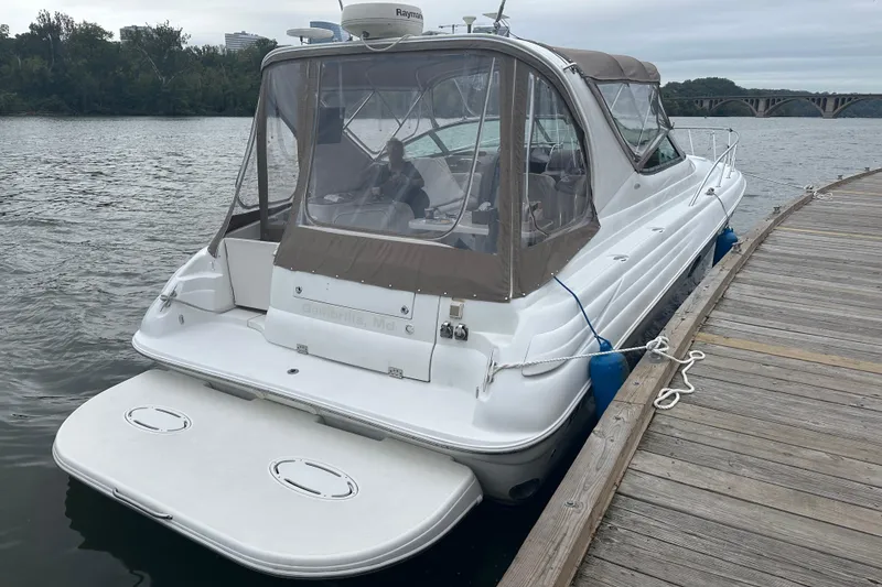 Slide: The Image of 2004 Larson 370 boat docked by a wooden pier on a calm river. - 2