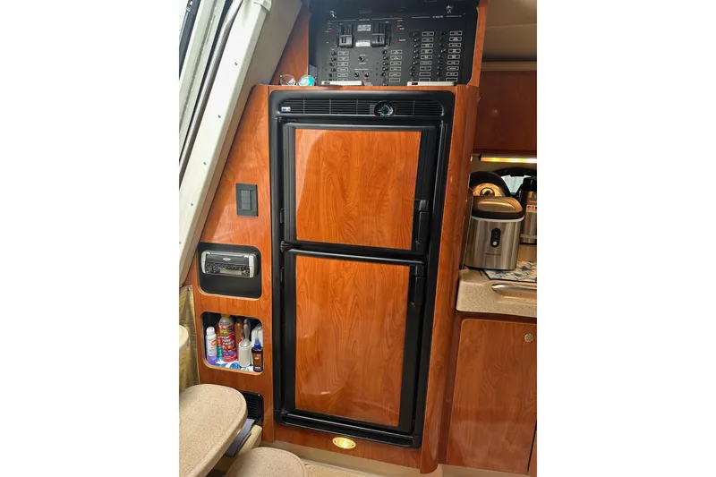 Slide: The Image of 2004 Larson 370 yacht interior with wood-paneled refrigerator and control panel. - 7