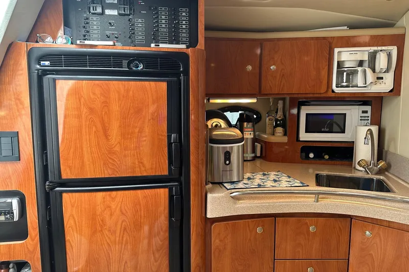 Slide: The Image of 2004 Larson 370 yacht kitchen with wood cabinetry, fridge, microwave, and sink. - 8