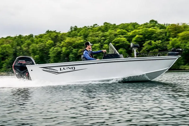 Slide: The Image of 2026 Lund 1775 Adventure Sport boat with Mercury 115 engine, parked outdoors. - 2