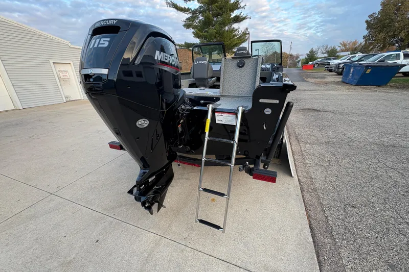 Slide: The Image of 2026 Lund 1775 Adventure Sport boat with Mercury 115 engine and ladder, parked outdoors. - 28