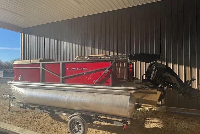 Slide: The Image of 2026 Lowe LS 170 pontoon boat with Mercury outboard motor, parked under a metal roof. - 3