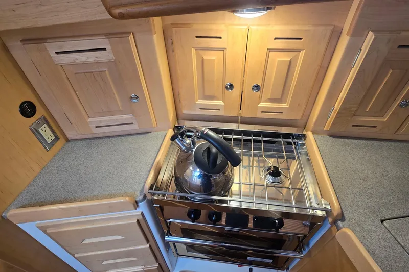 Slide: The Image of Compact kitchen in 2018 Tartan 345 yacht with stove, kettle, and wooden cabinets. - 14