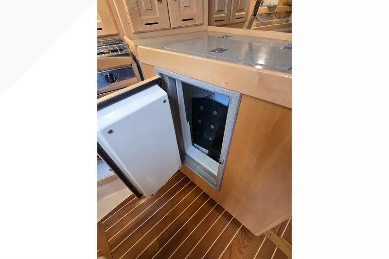 Slide: The Image of Open refrigerator in Tartan 345 yacht kitchen, showcasing wooden cabinetry and flooring, 2018 model. - 17