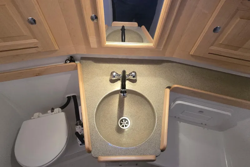 Slide: The Image of 2018 Tartan 345 yacht bathroom with sink, mirror, and wooden cabinetry. - 18