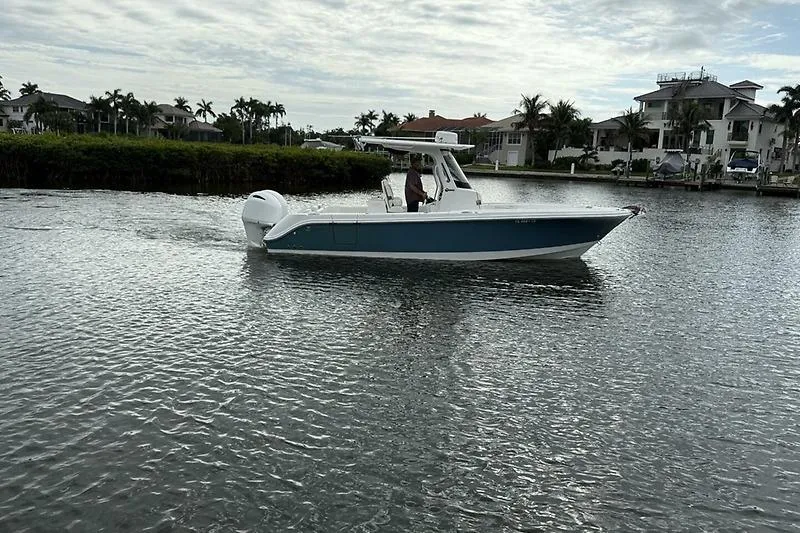 Slide: The Image of 2022 Edgewater 262CC boat cruising on a calm waterway near waterfront homes. - 11