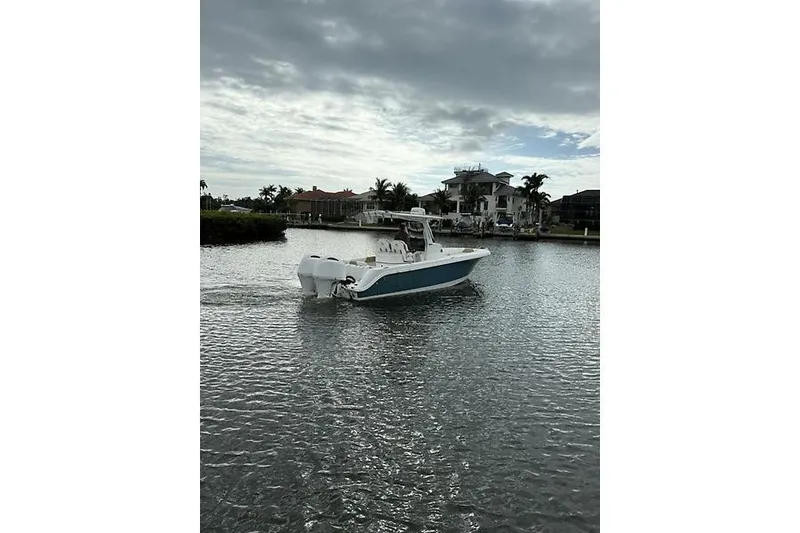 Slide: The Image of 2022 Edgewater 262CC boat on a calm waterway with cloudy sky backdrop. - 12