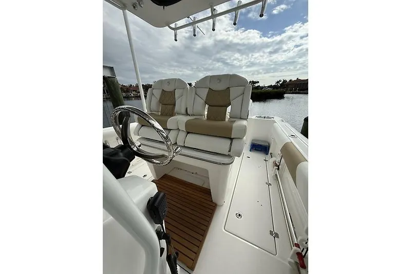 Slide: The Image of 2022 Edgewater 262CC boat interior with plush seating and steering wheel, docked by the water. - 15
