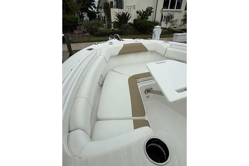 Slide: The Image of 2022 Edgewater 262CC boat interior with white and tan seating, featuring a table and cup holder. - 19