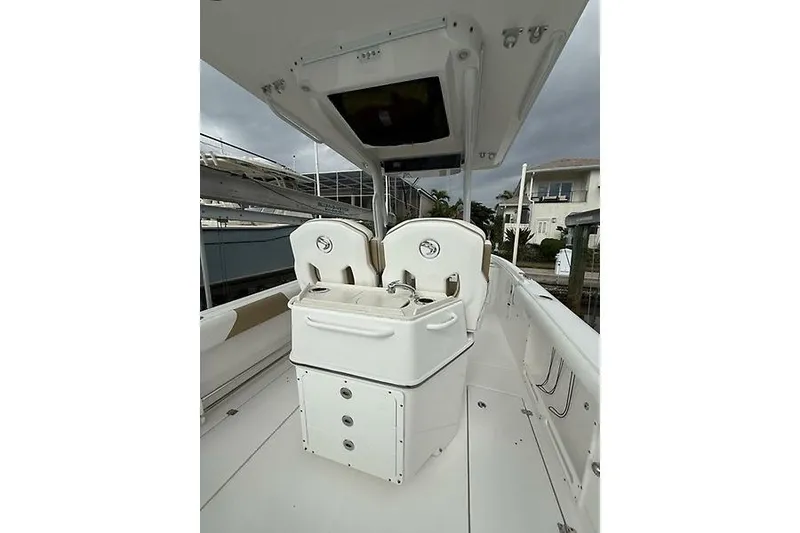Slide: The Image of 2022 Edgewater 262CC boat interior with dual seats and storage, docked near waterfront homes. - 22