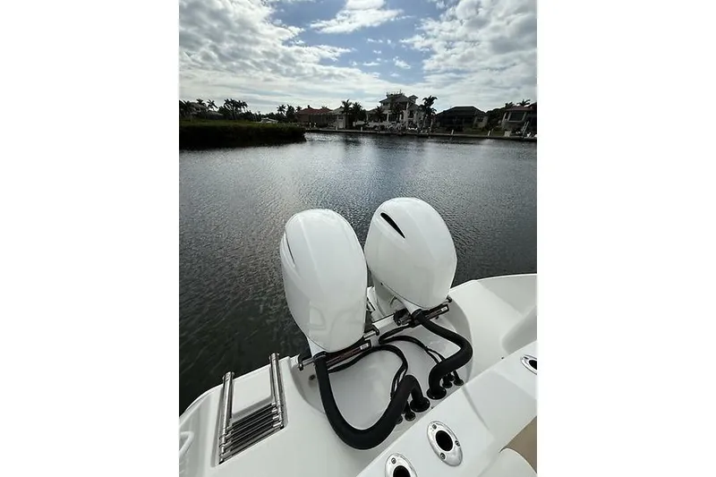 Slide: The Image of 2022 Edgewater 262CC boat with dual outboard motors on a calm waterway. - 26