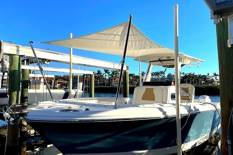 Slide: The Image of 2022 Edgewater 262CC boat docked with sunshade, clear blue sky background. - 30