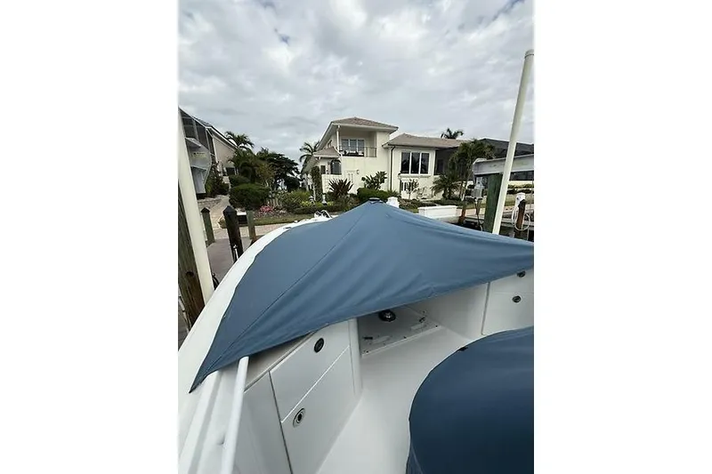 Slide: The Image of 2022 Edgewater 262CC boat docked near waterfront home under cloudy sky. - 32