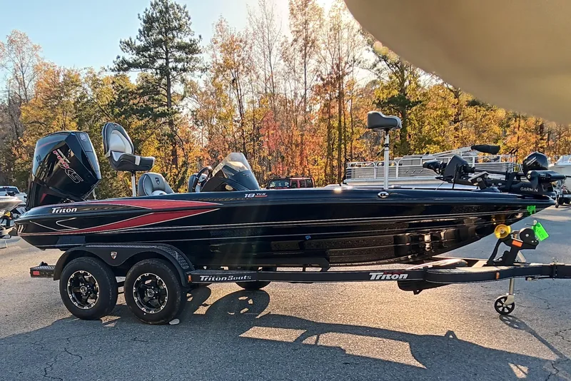 Slide: The Image of 2026 Triton 18 TrX boat on trailer, parked outdoors with autumn trees in background. - 4