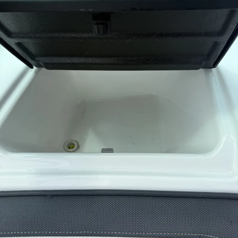 Slide: The Image of An open storage compartment on a 2014 Yamaha 212X boat, featuring a drain at the bottom. - 28
