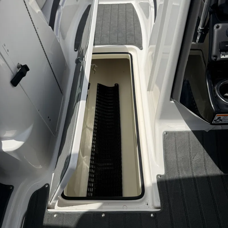 Slide: The Image of An open storage compartment on a 2014 Yamaha 212X boat, featuring gray carpeting. - 18