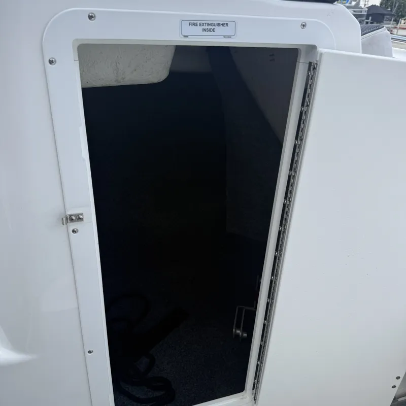 Slide: The Image of An open storage compartment door on a 2014 Yamaha 212X boat. A sign indicates a fire extinguisher inside. - 19