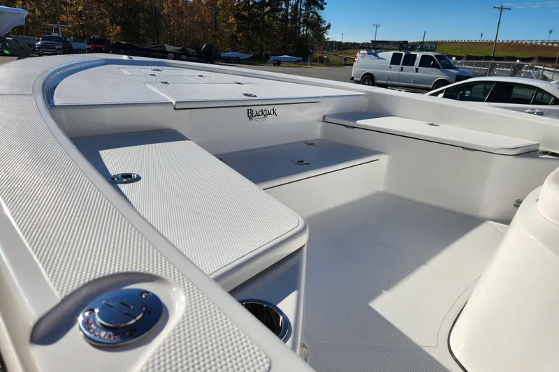 Slide: The Image of 2026 BlackJack 224 boat interior with seating and storage, parked outdoors. - 11