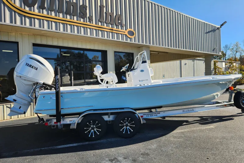 Slide: The Image of 2026 BlackJack 224 boat with Yamaha engine on trailer outside dealership. - 2