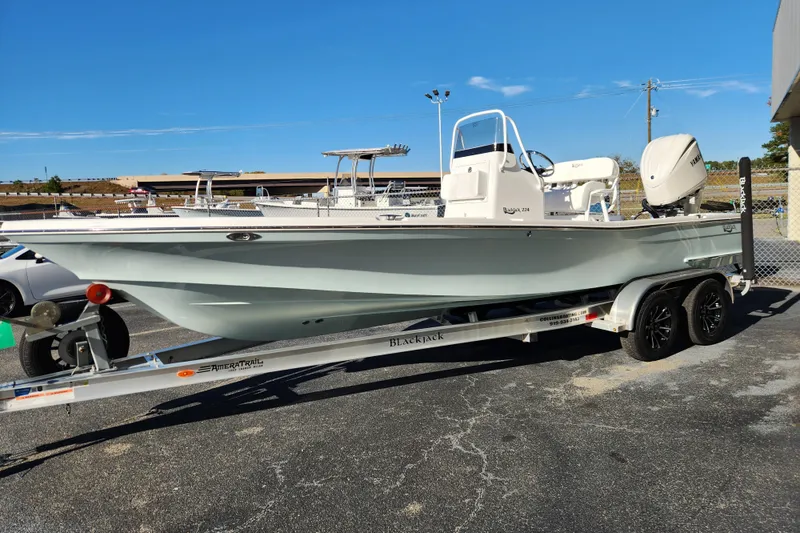 Slide: The Image of 2026 BlackJack 224 boat on trailer, parked outdoors under clear blue sky. - 6