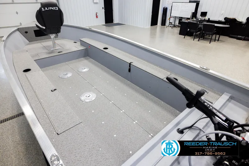 Slide: The Image of 2026 Lund 1600 Fury Tiller boat interior in showroom with seating and controls. - 10