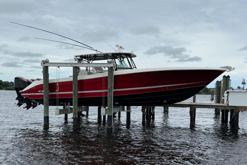 Slide: The Image of 2013 Hydra-Sports 42 boat on lift, red and black design, docked by the water. - 3