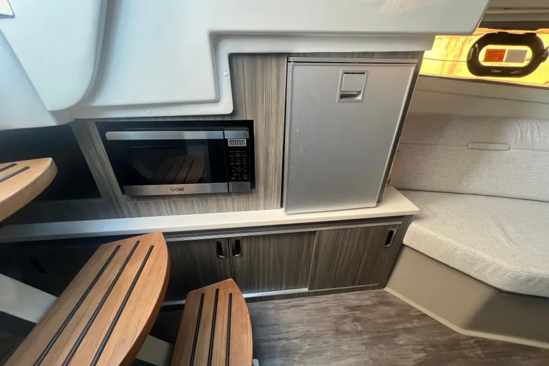 Slide: The Image of Interior of 2025 Sea Ray Sundancer 320 Coupe with microwave and seating area. - 10