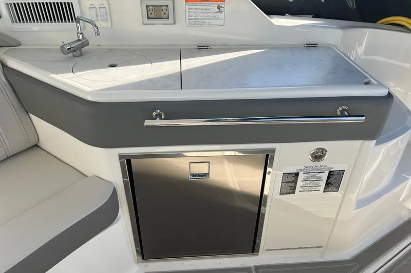 Slide: The Image of 2025 Sea Ray Sundancer 320 Coupe kitchenette with sink, countertop, and stainless steel fridge. - 5