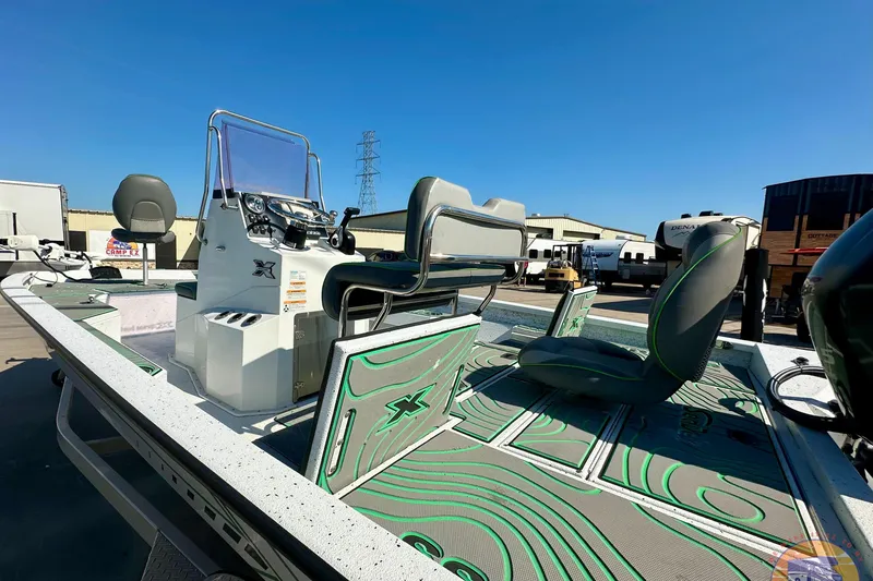 Slide: The Image of 2024 Xpress H20B Bay boat with modern seating and control console, parked outdoors. - 23