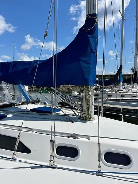 Slide: The Image of Sailboat Catalina 320, 2000 model, docked with blue sail cover, clear sky background. - 16